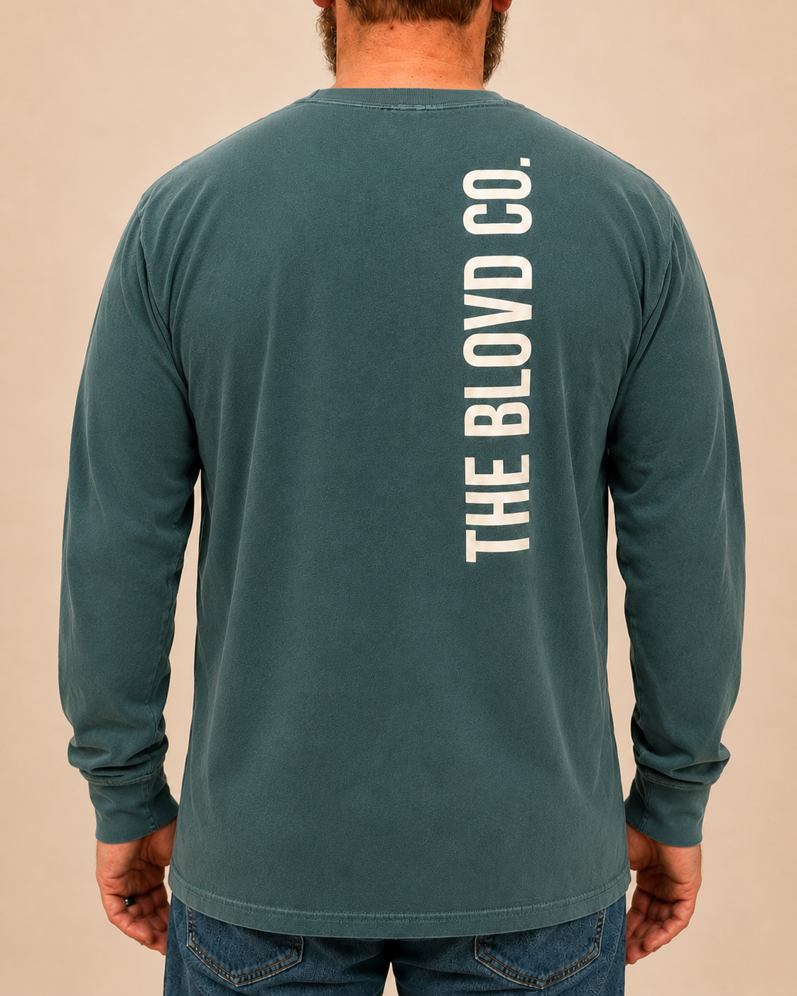 THE BLOVD Lion Signature Comfort Colors 6014 Blue Spruce long sleeve with Soft Linen vertical THE BLOVD CO. back wordmark, approved male rear studio view