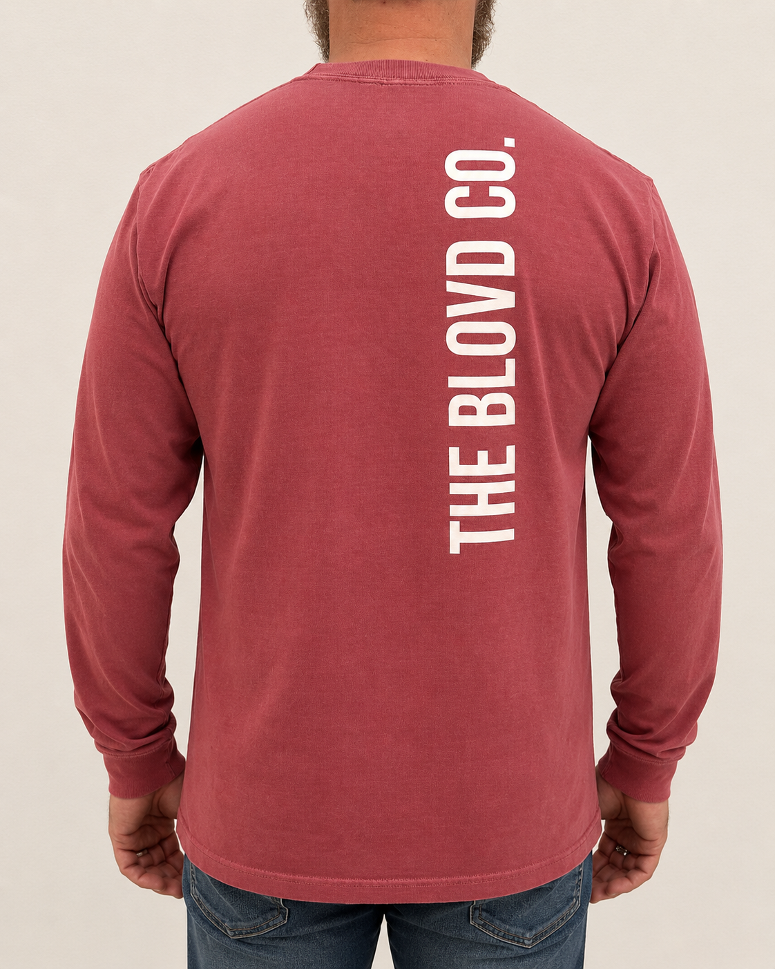 THE BLOVD Lion Signature Comfort Colors 6014 Crimson long sleeve with white vertical THE BLOVD CO. back wordmark, approved tightly cropped male rear studio view