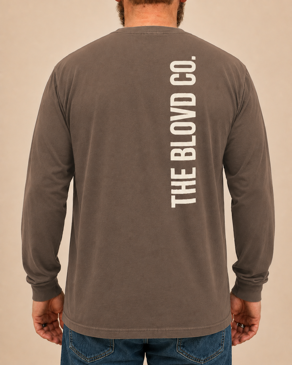 THE BLOVD Lion Signature Comfort Colors 6014 Espresso long sleeve with Warm Ivory vertical THE BLOVD CO. back wordmark, approved male rear studio view