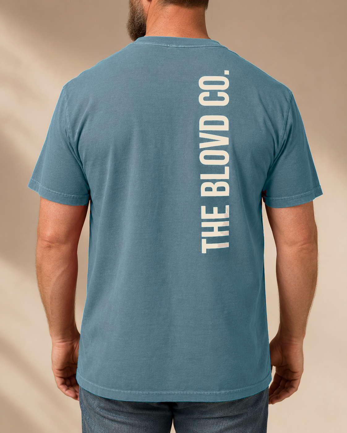 THE BLOVD Lion Signature Blue Jean T-shirt with Warm Ivory vertical back wordmark, studio back view